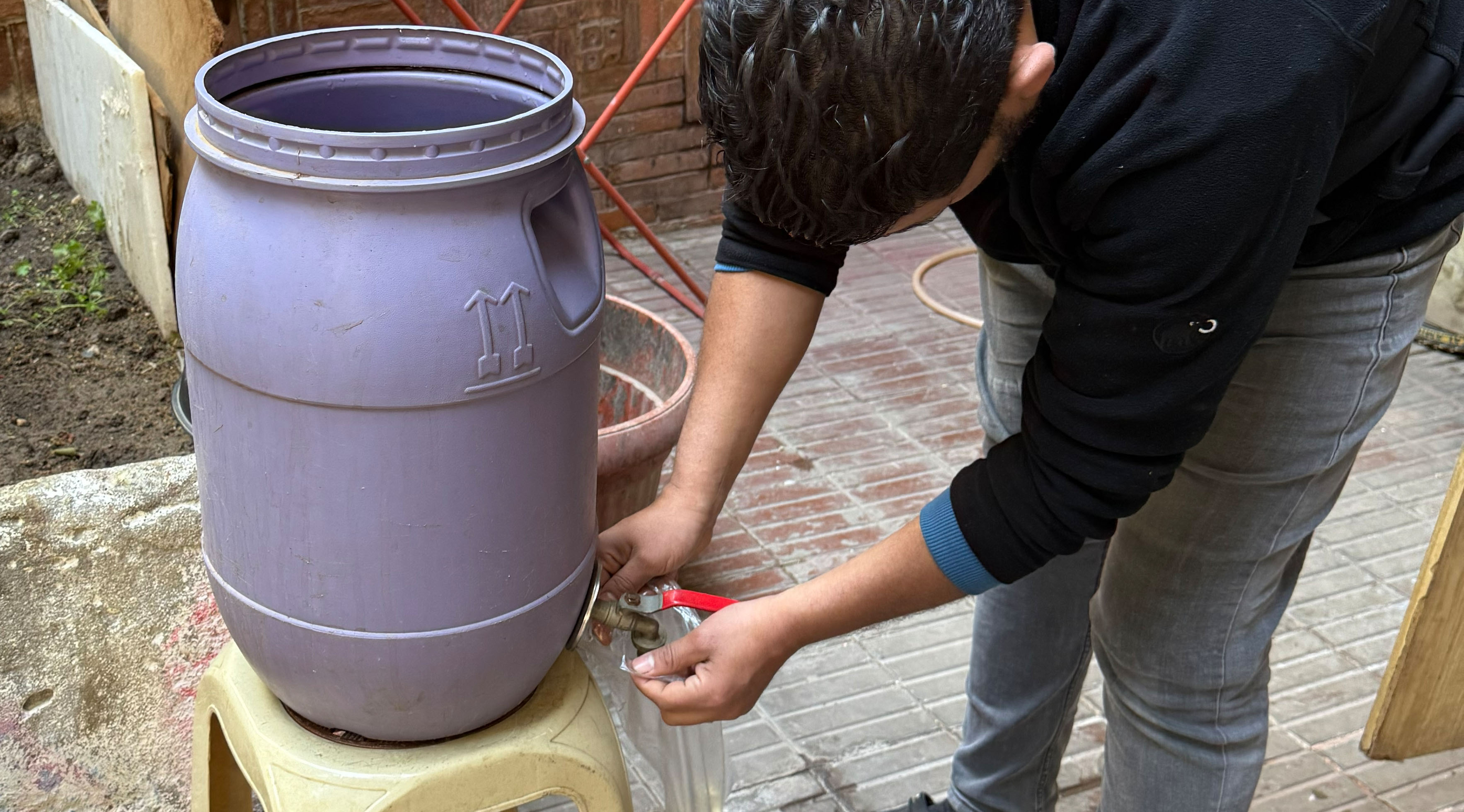 A man getting water out of a plastic water jug with a spigot.